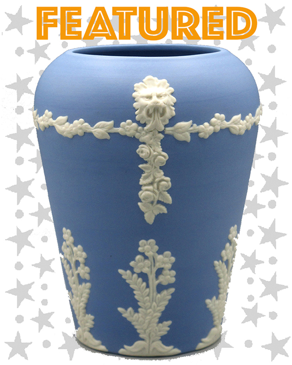 Blue vase with white flower and vine motifs and a lions head atop each side of the vase.
